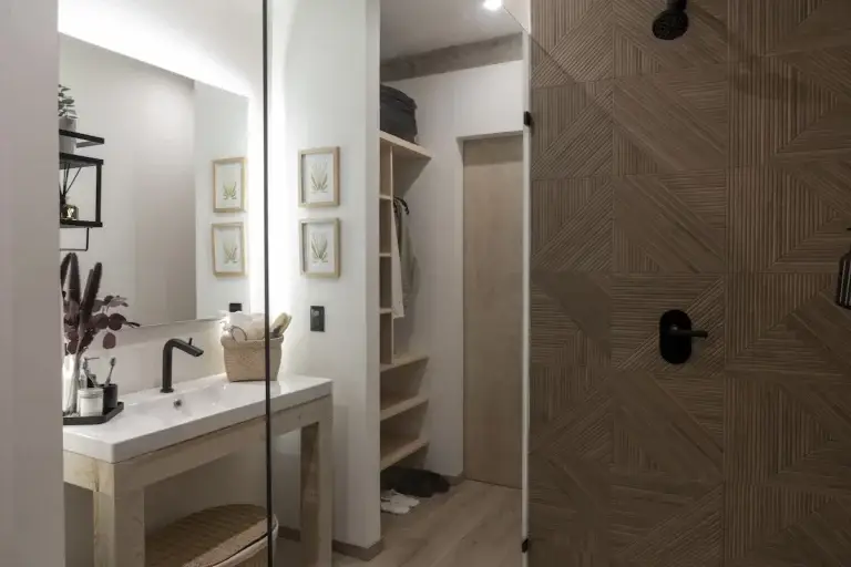 Vista del baño. Lavamanos de ceramica con estructura de madera. Regadera con acabado en porcelanato con griferia Helvex. Closet de madera de pino